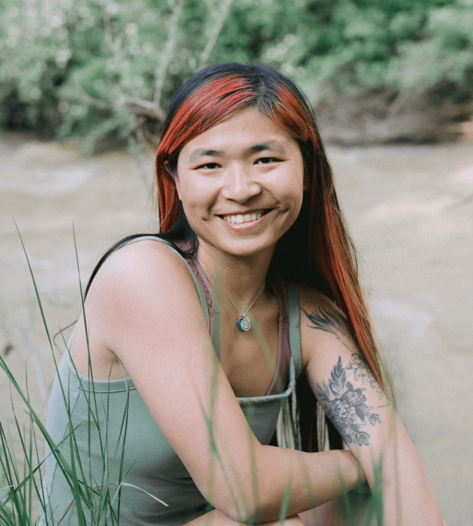 Portrait of Niki DiGaetano, an Asian-American woman sitting by a river